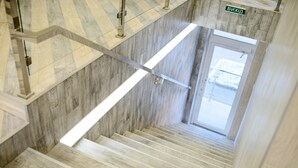 A staircase with wooden steps and metal handrails, leading to a door with a sign above it. - Urban Hotel (Lviv)