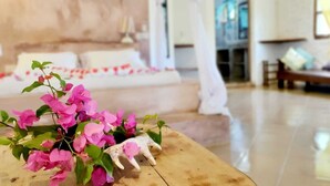 Ein geräumiges Zimmer mit einem großen Bett, einem Holztisch mit Blumen und einem Sofa.