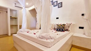 Ein Schlafzimmer mit Baldachinbett, weißer Bettwäsche und einem Zierkissen.