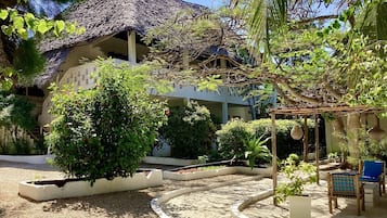 Un complexe hôtelier doté d’un bâtiment à toit de chaume, d’un jardin avec des allées de gravier et d’un espace extérieur aménagé pour s’asseoir.