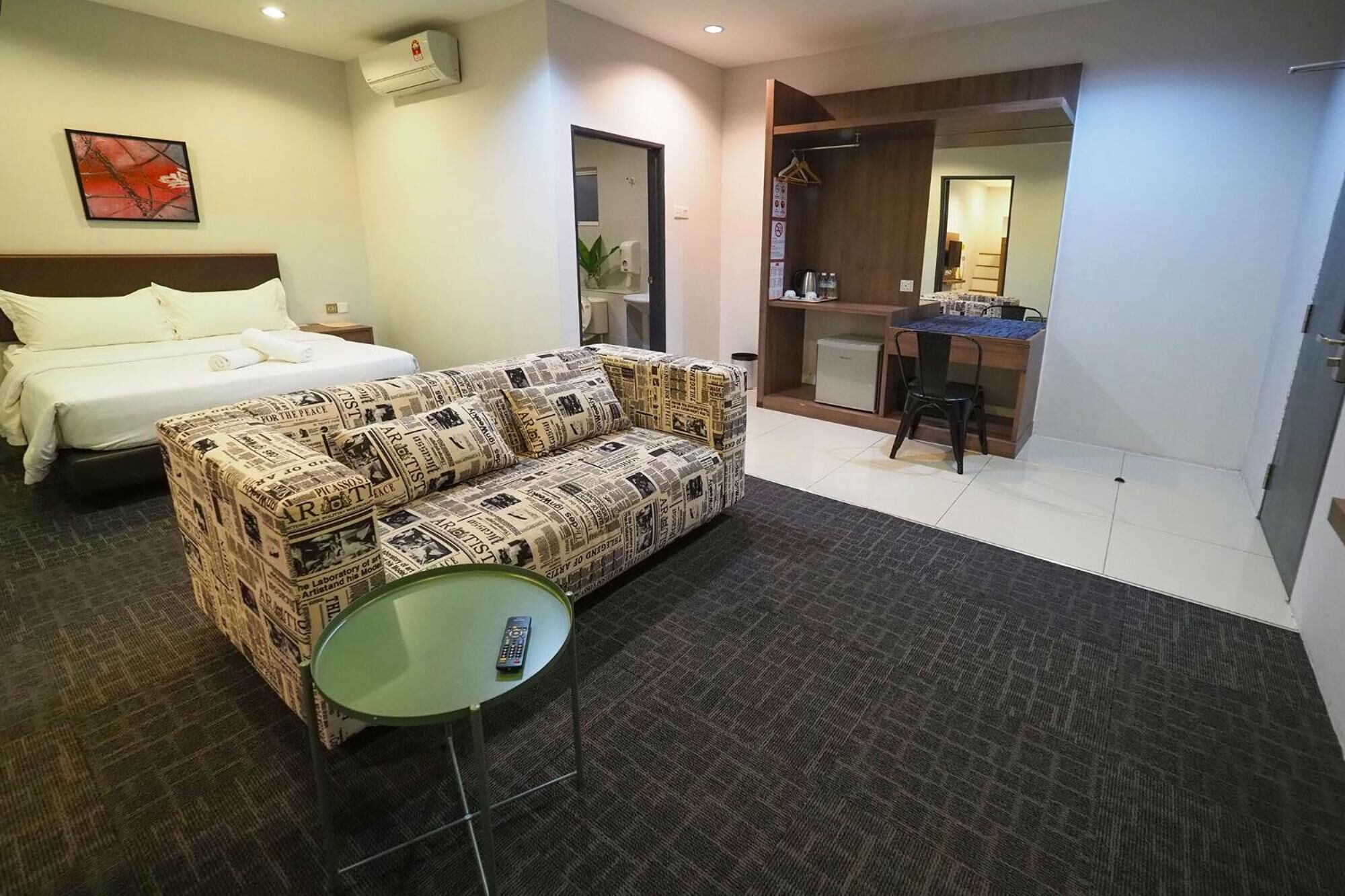 Una habitación de hotel con cama, sofá, una mesita y un escritorio con silla.