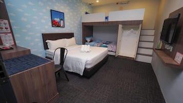 A hotel room with a bed, a desk, a chair, a bunk bed, and a television.
