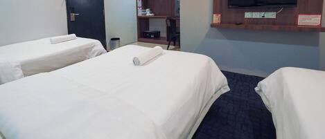 A hotel room with two single beds, a TV mounted on the wall, and a small desk with a chair.
