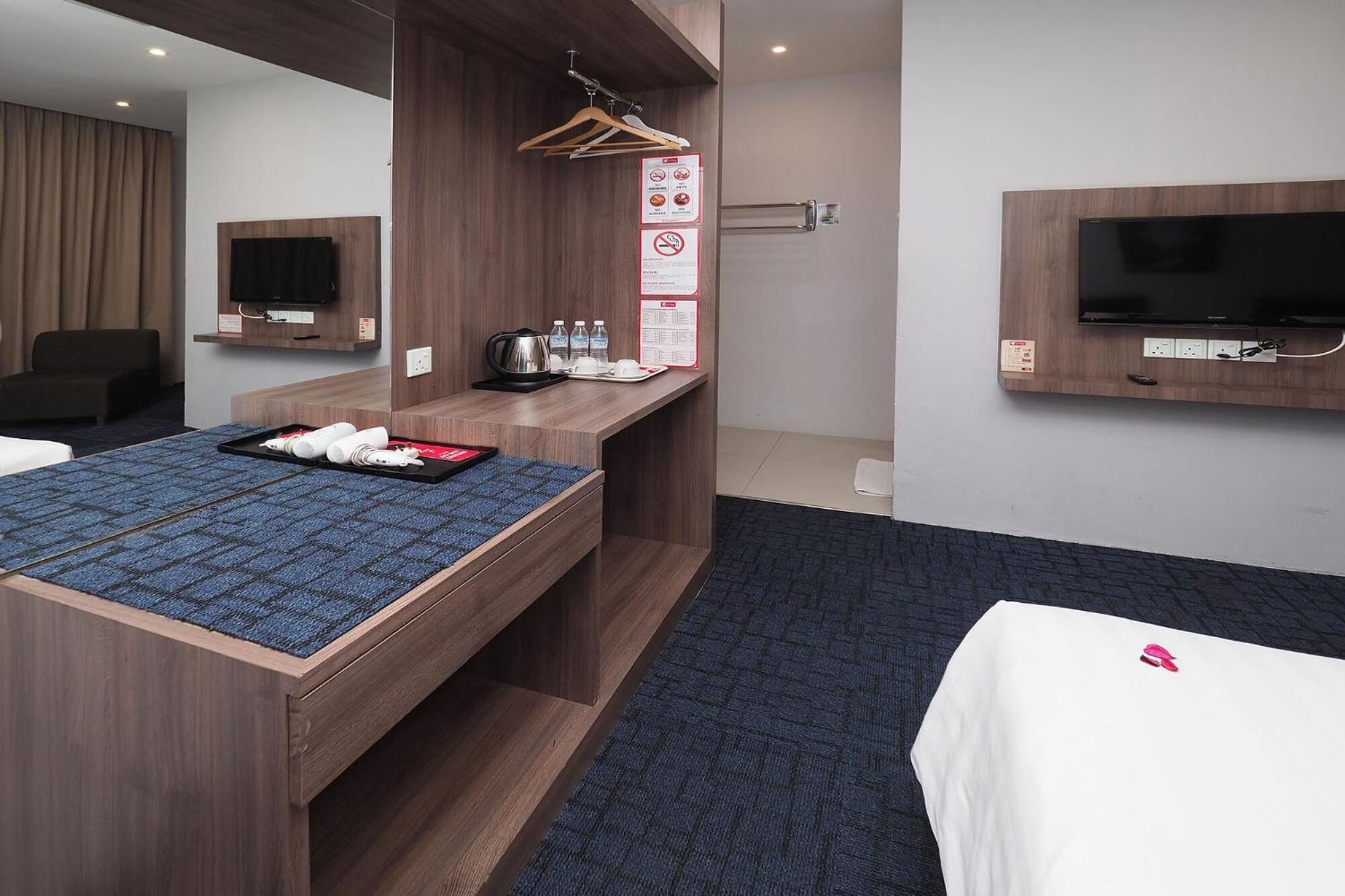 Quarto de hotel com escrivaninha de madeira, televisão de tela plana, sofá e cama.