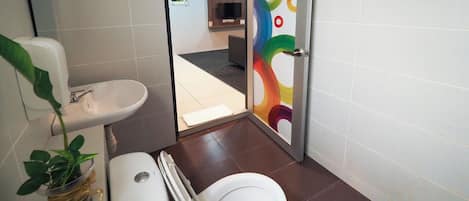Een badkamer met toilet, wastafel en een kamerplant.