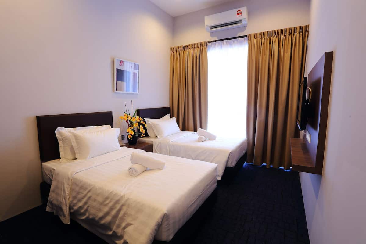 Habitación de hotel con dos camas, un televisor de pantalla plana, aire acondicionado y una ventana con cortinas.