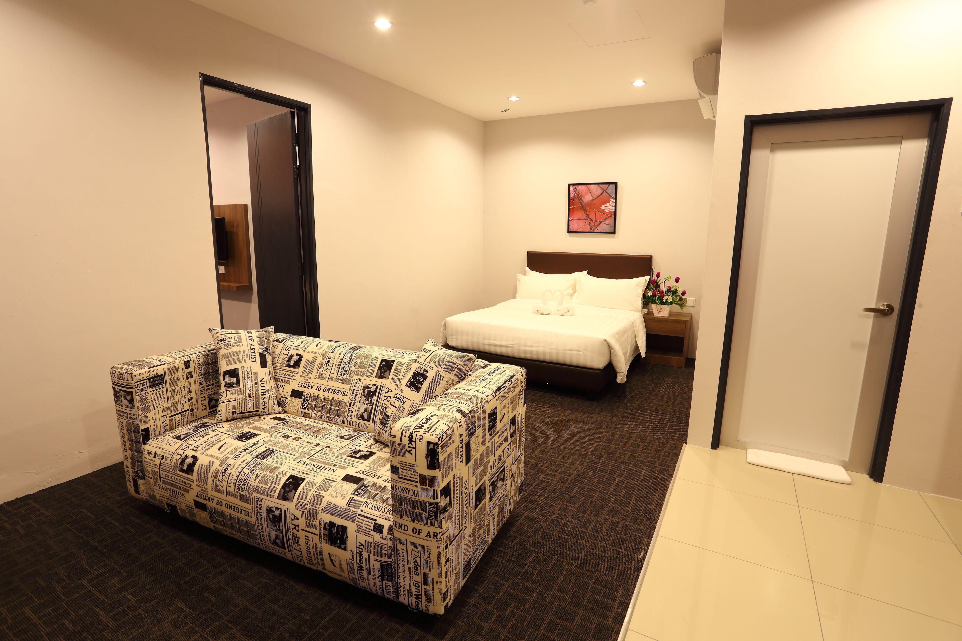 Una habitación de hotel con un sofá, una cama y una puerta.