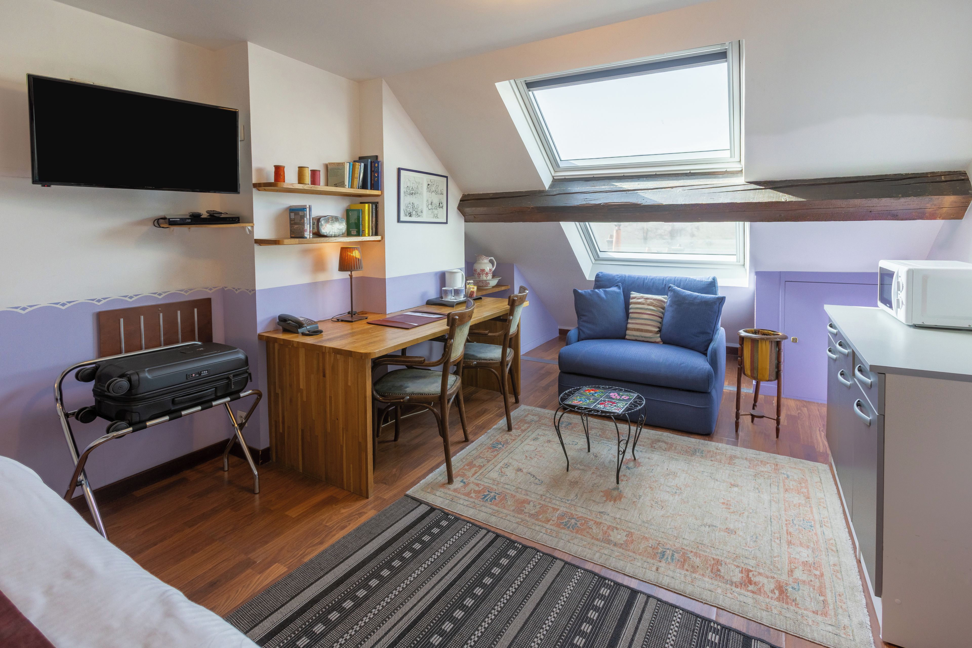 Un espace de vie compact comprenant un lit en mezzanine, un coin repas, un canapé et une kitchenette.