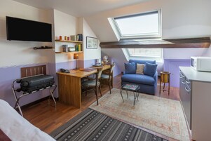 Un ambiente compatto con un letto a soppalco, zona pranzo, divano e angolo cottura.