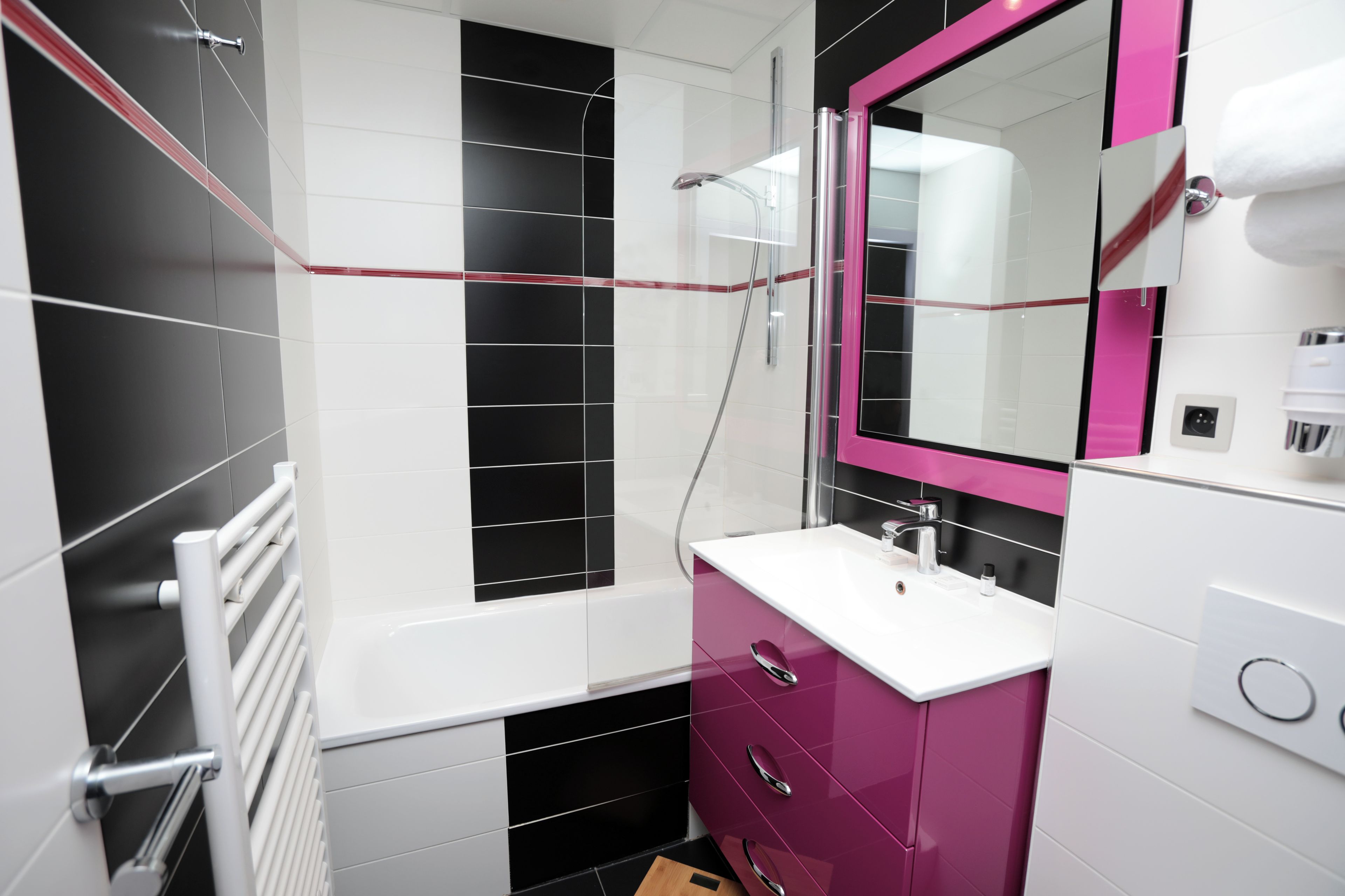 A modern bathroom with a white bathtub, a pink vanity, and a large mirror.