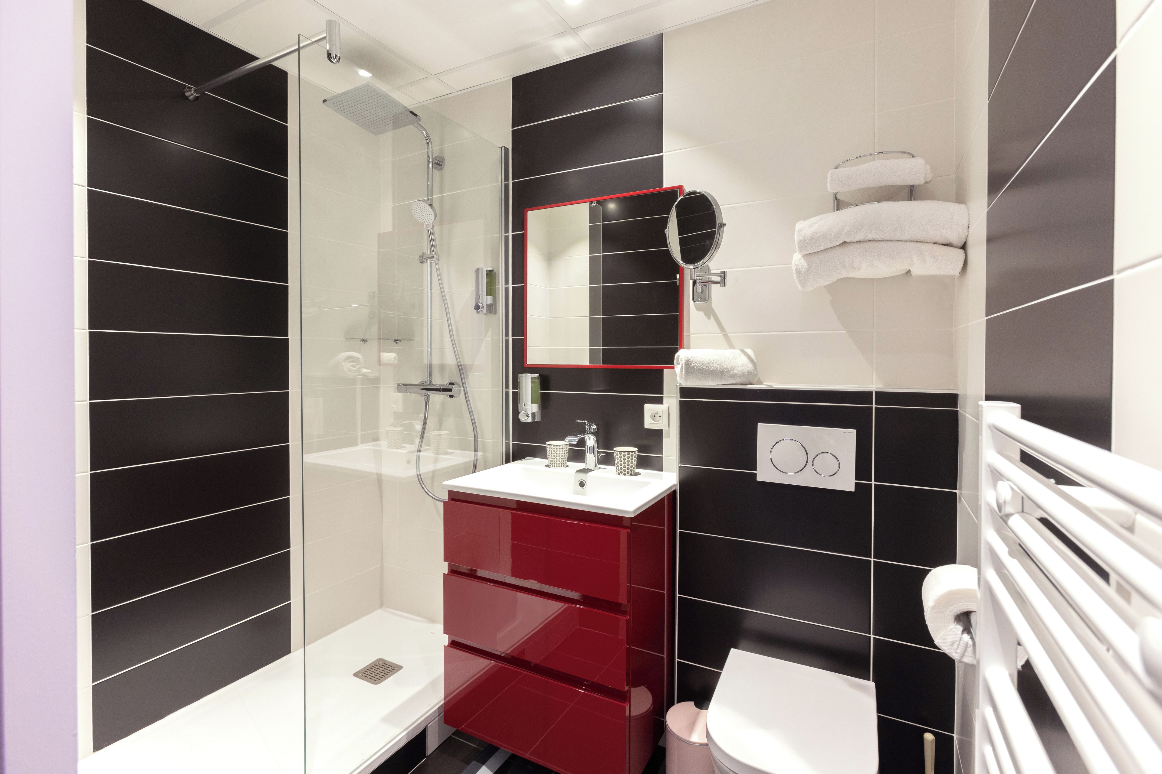 Une salle de bain moderne avec une douche à parois de verre, un meuble-lavabo rouge et des toilettes blanches.