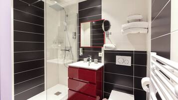 A modern bathroom with a glass-enclosed shower, a red vanity, and a white toilet.