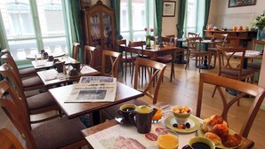 Espaço de refeições com mesas e cadeiras de madeira, serviço de café da manhã incluído e vista para o exterior.