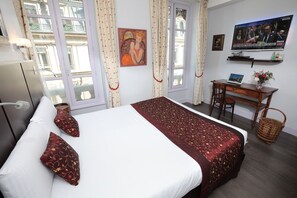 A hotel room with a bed, a desk, a television, and a window with curtains. - Hôtel des Célestins (Lyon)