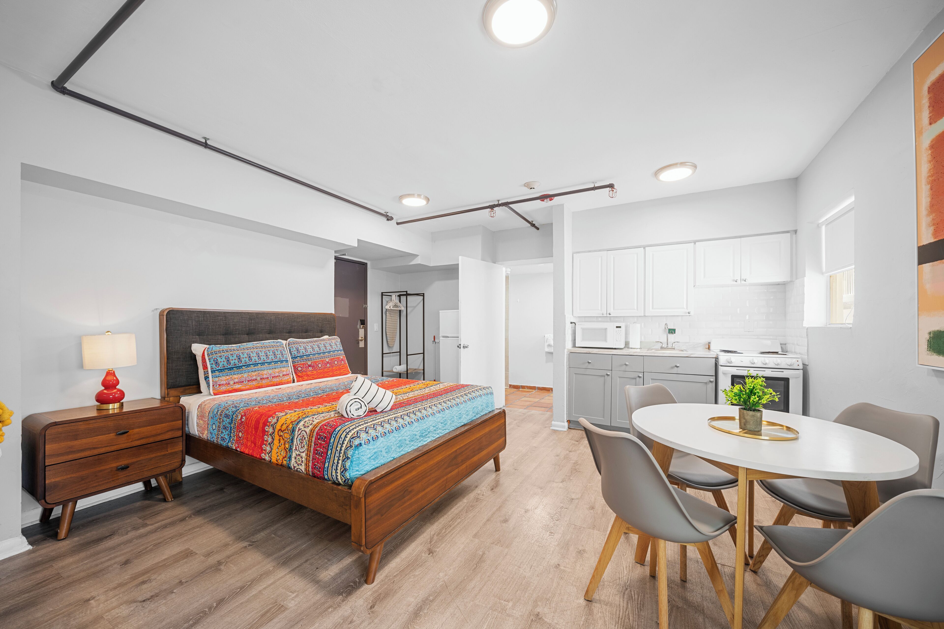 A modern bedroom with a wooden bed, bedside tables, and a dining area with a table and chairs.