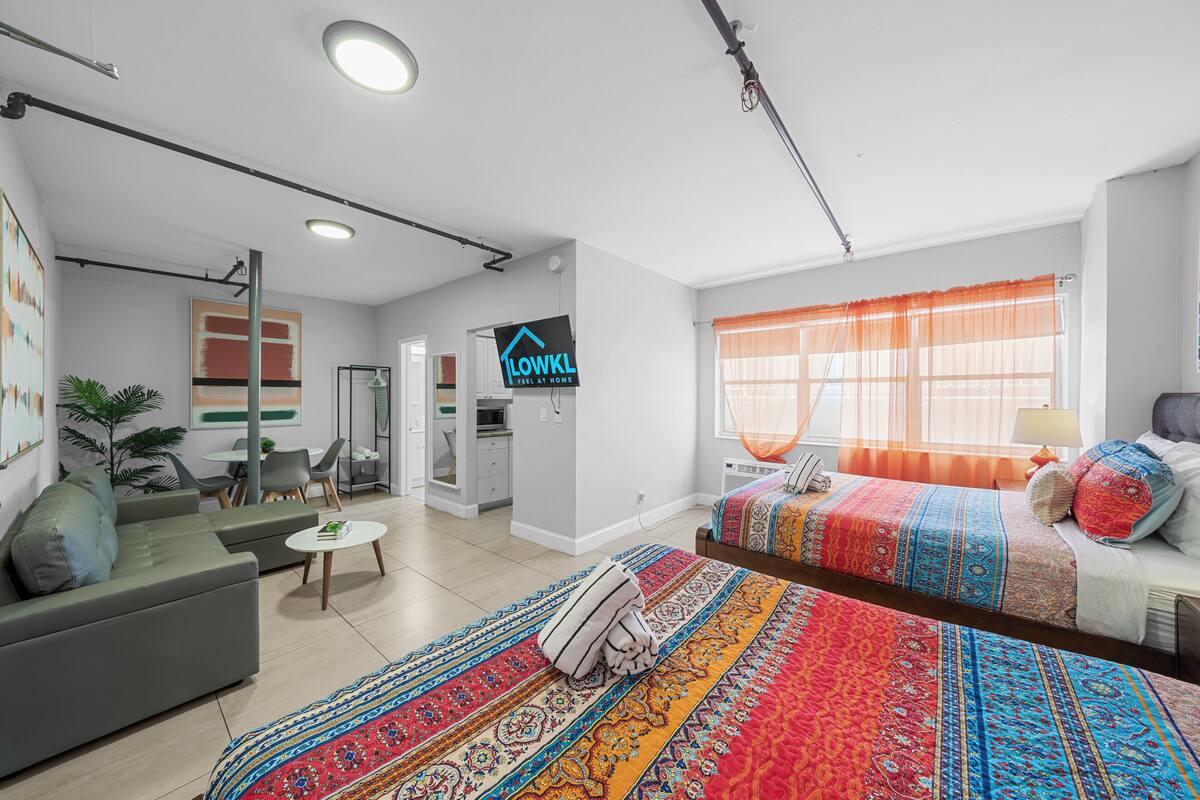 Ein modernes Hotelzimmer mit einem großen Bett, einer Couch, einer Essecke und einer Küche.