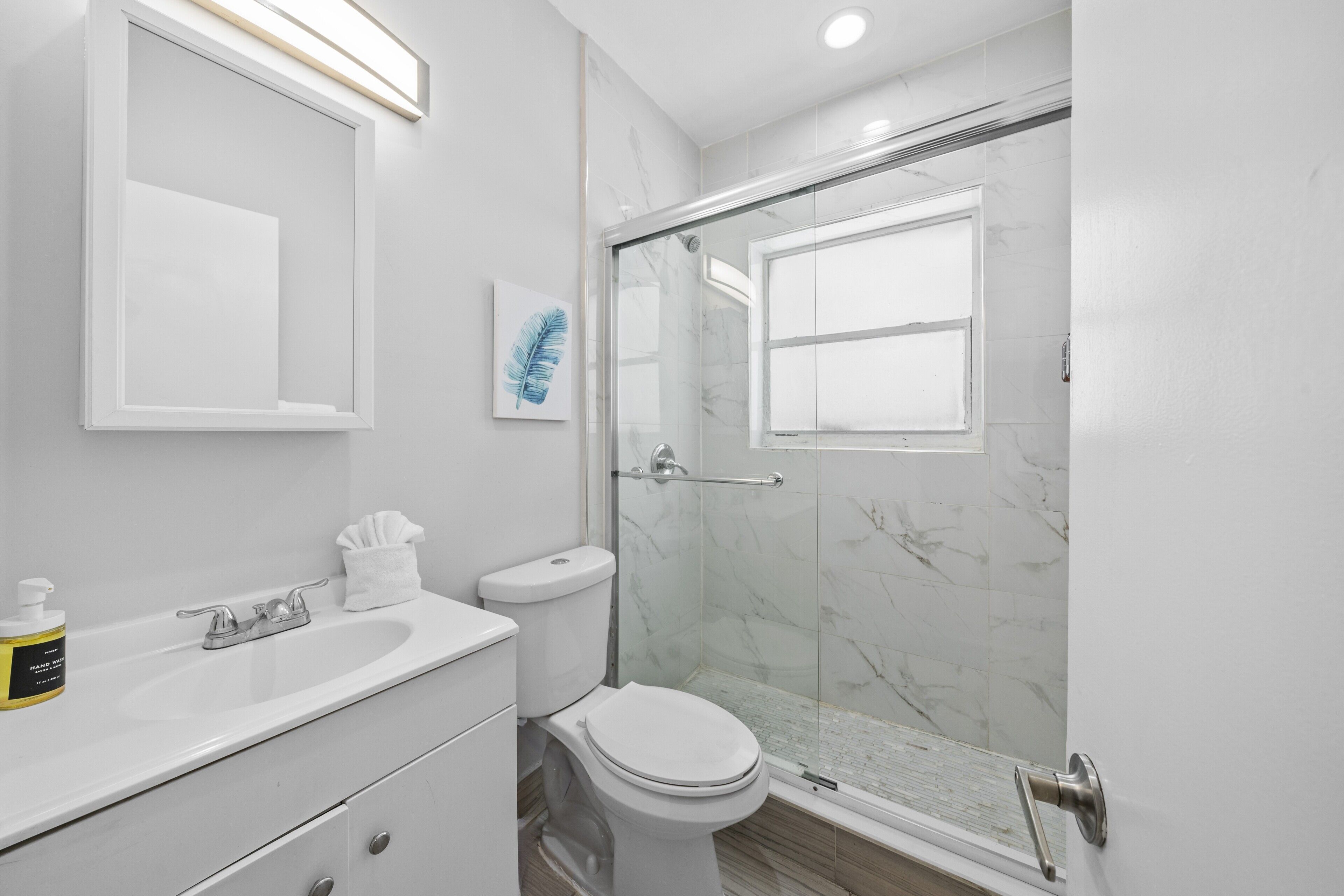 A modern bathroom with a white sink, toilet, and glass-enclosed shower.