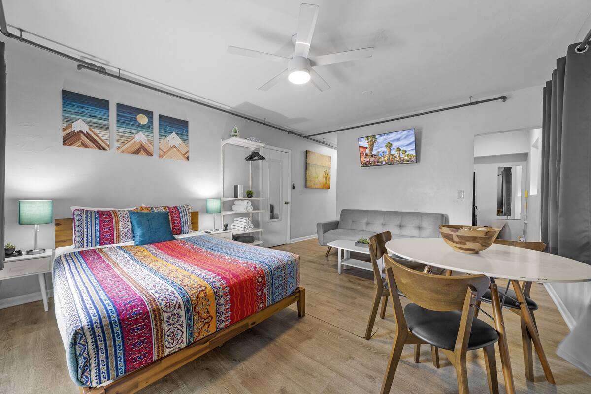 Ein modernes Schlafzimmer mit einem großen Bett, einem Schreibtisch, einer Couch und einem Esstisch.