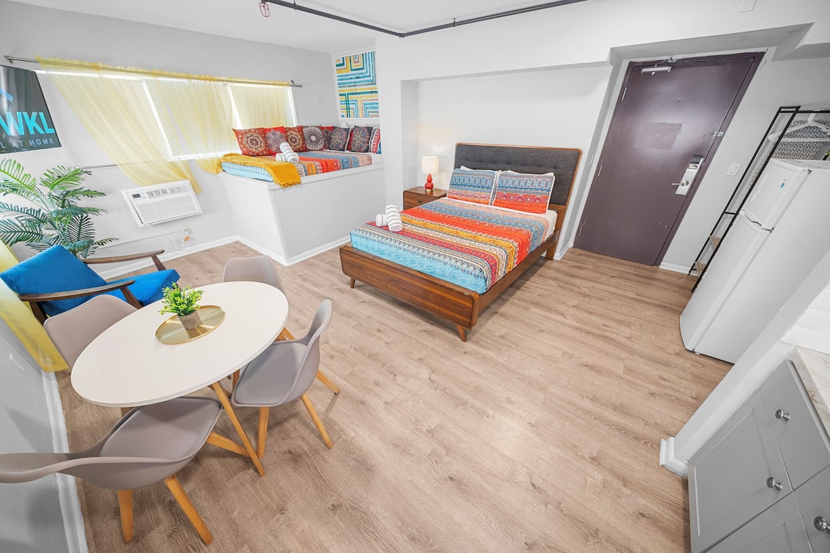 Ein gemütliches Schlafzimmer mit Bett, Nachttisch und einem kleinen Fenster mit Vorhängen.