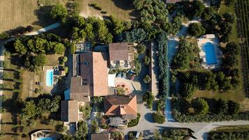 An aerial view of a residential area with multiple houses, a swimming pool, and a vineyard.