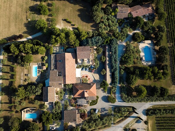 An aerial view of a residential area with multiple houses, a swimming pool, and a vineyard. - Le Clos Saint-Michel & Spa (Malaucene)