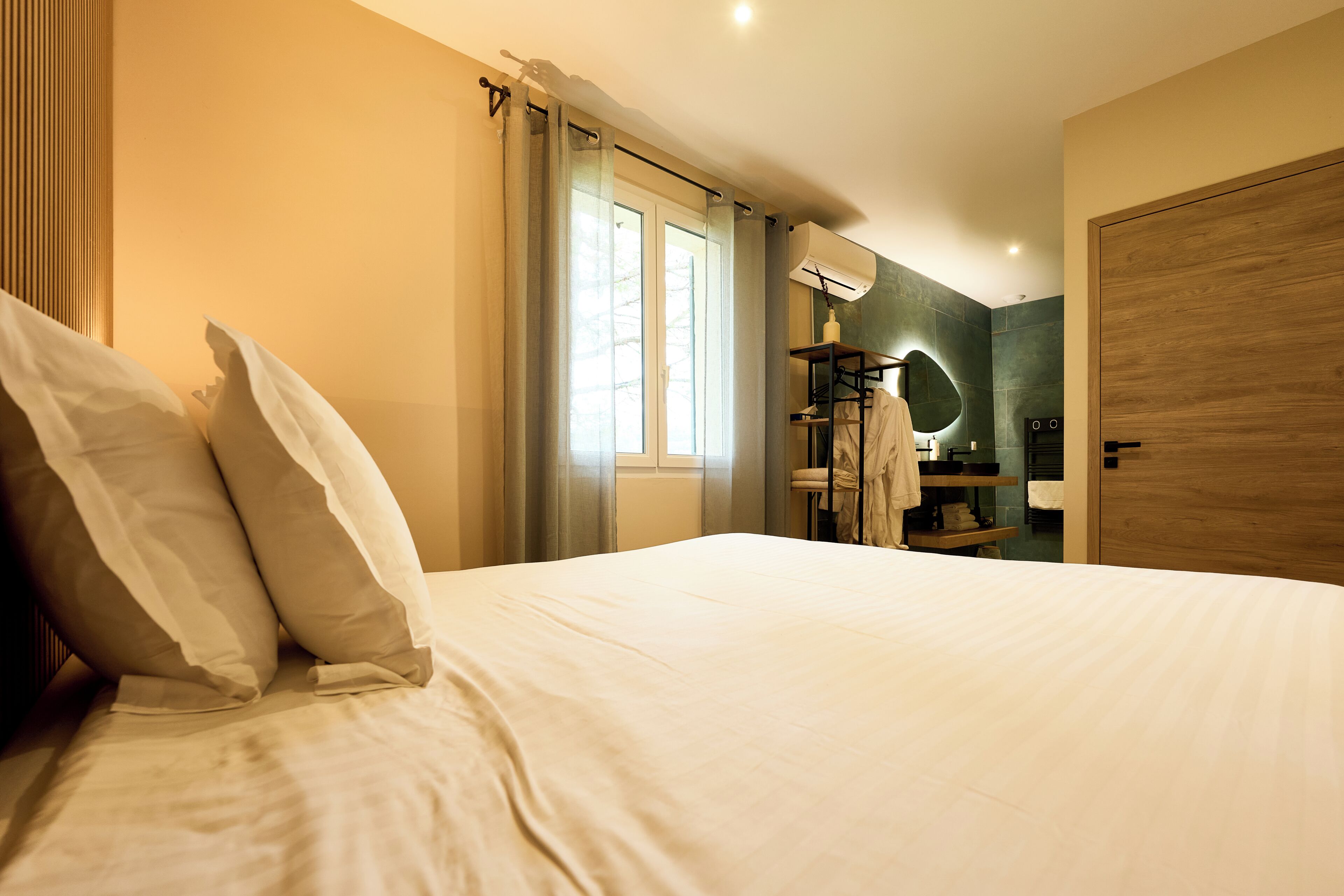 Una habitación de hotel con una cama, un baño con un espejo y una puerta de madera.