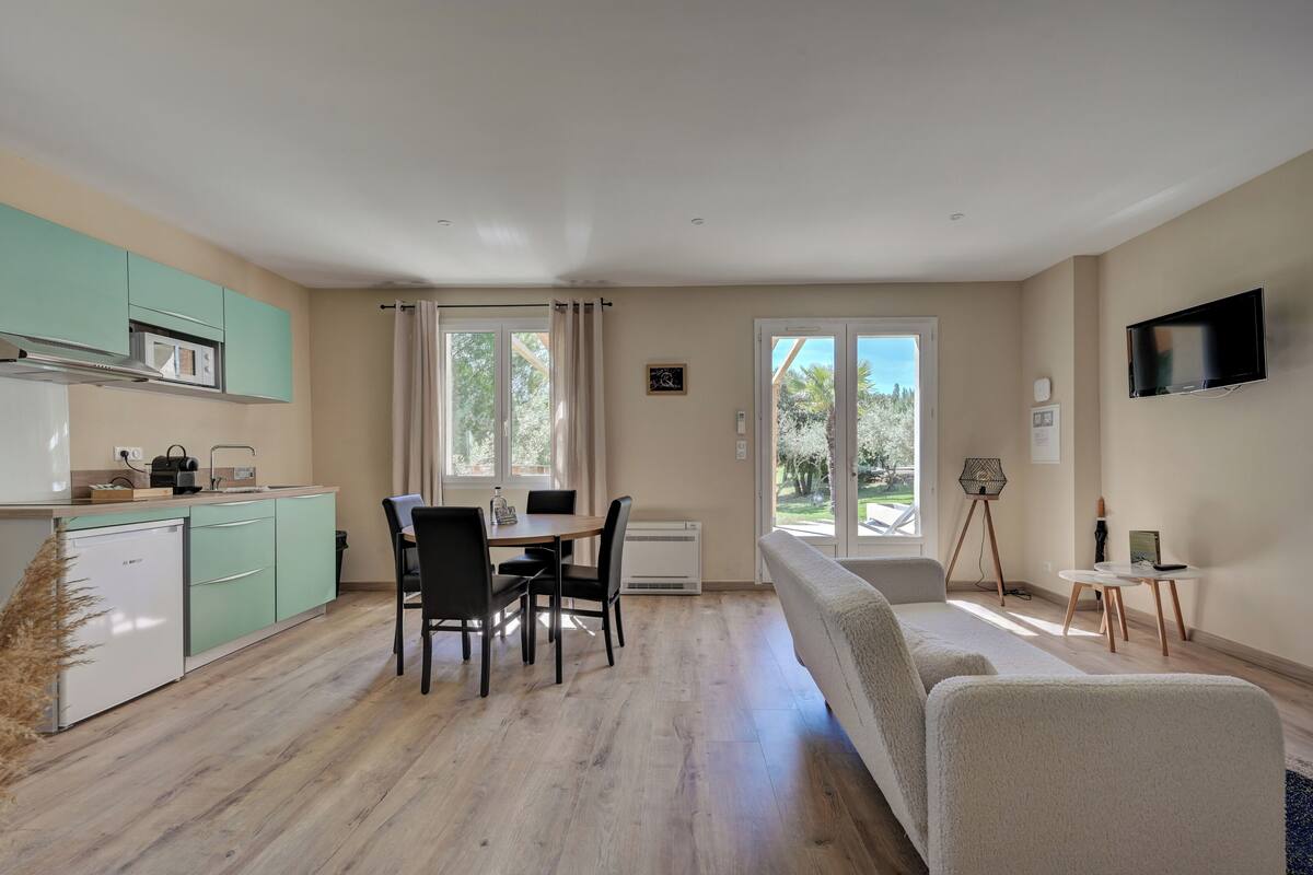 A modern kitchen with a dining area, a sofa, and a TV.