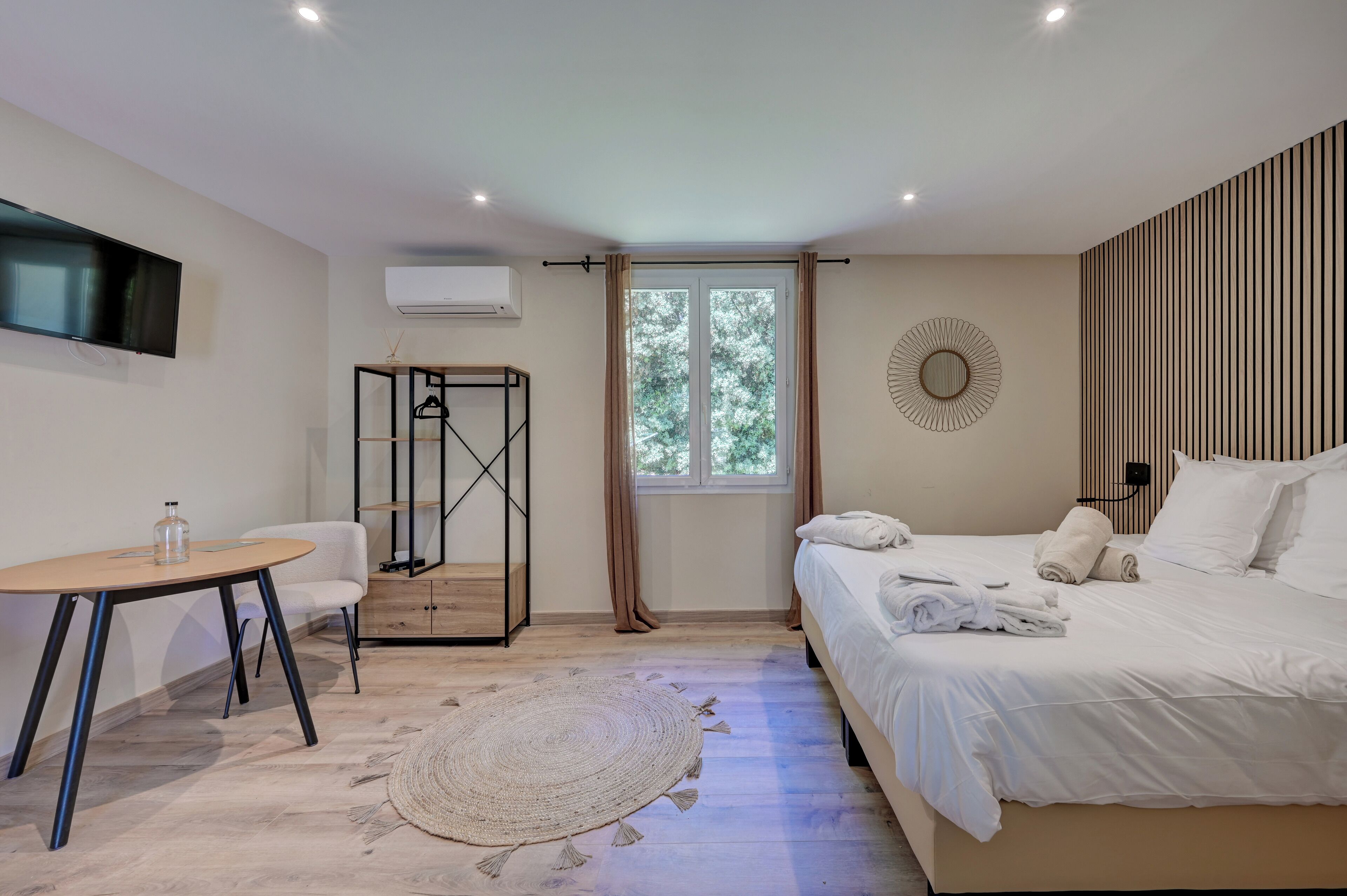 A modern bedroom with a bed, bedside table, and a hanging wardrobe.