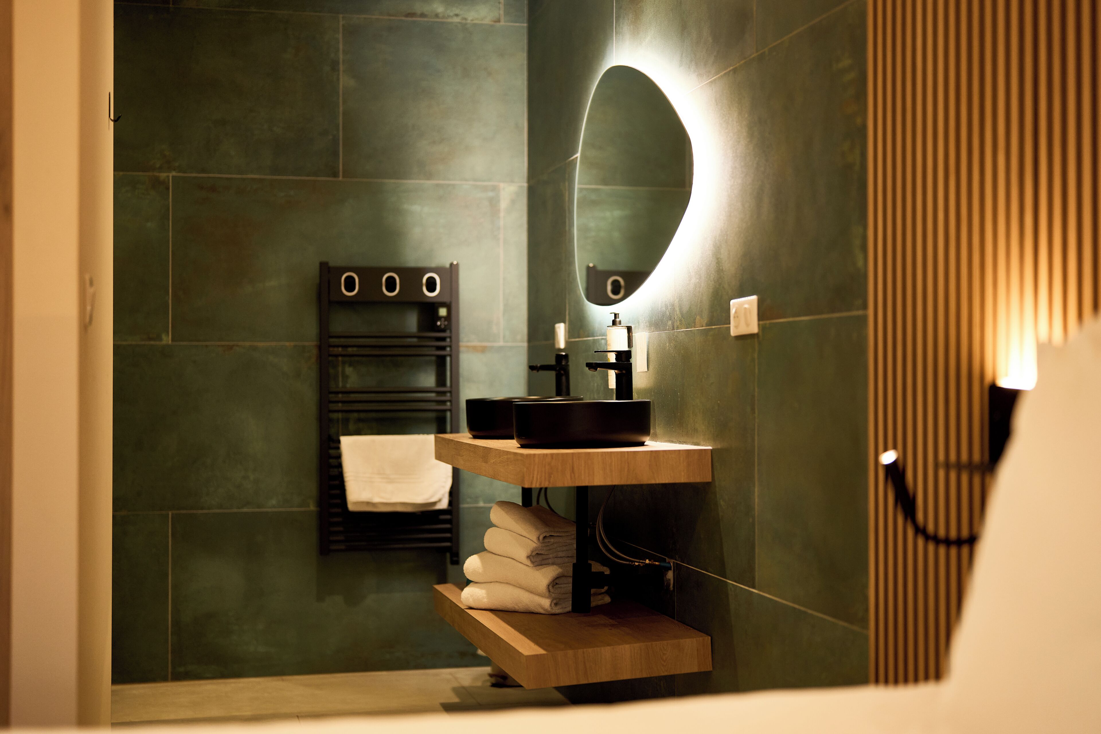 Un baño moderno con tocador de madera, perchero y espejo.