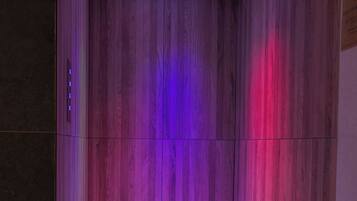 A wooden-paneled room with a ceiling light fixture and a strip of LED lighting on the floor.