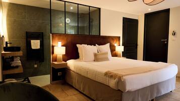 Une chambre d'hôtel avec un grand lit, des lampes de chevet, un miroir, une salle de bain avec un porte-serviettes et une porte.