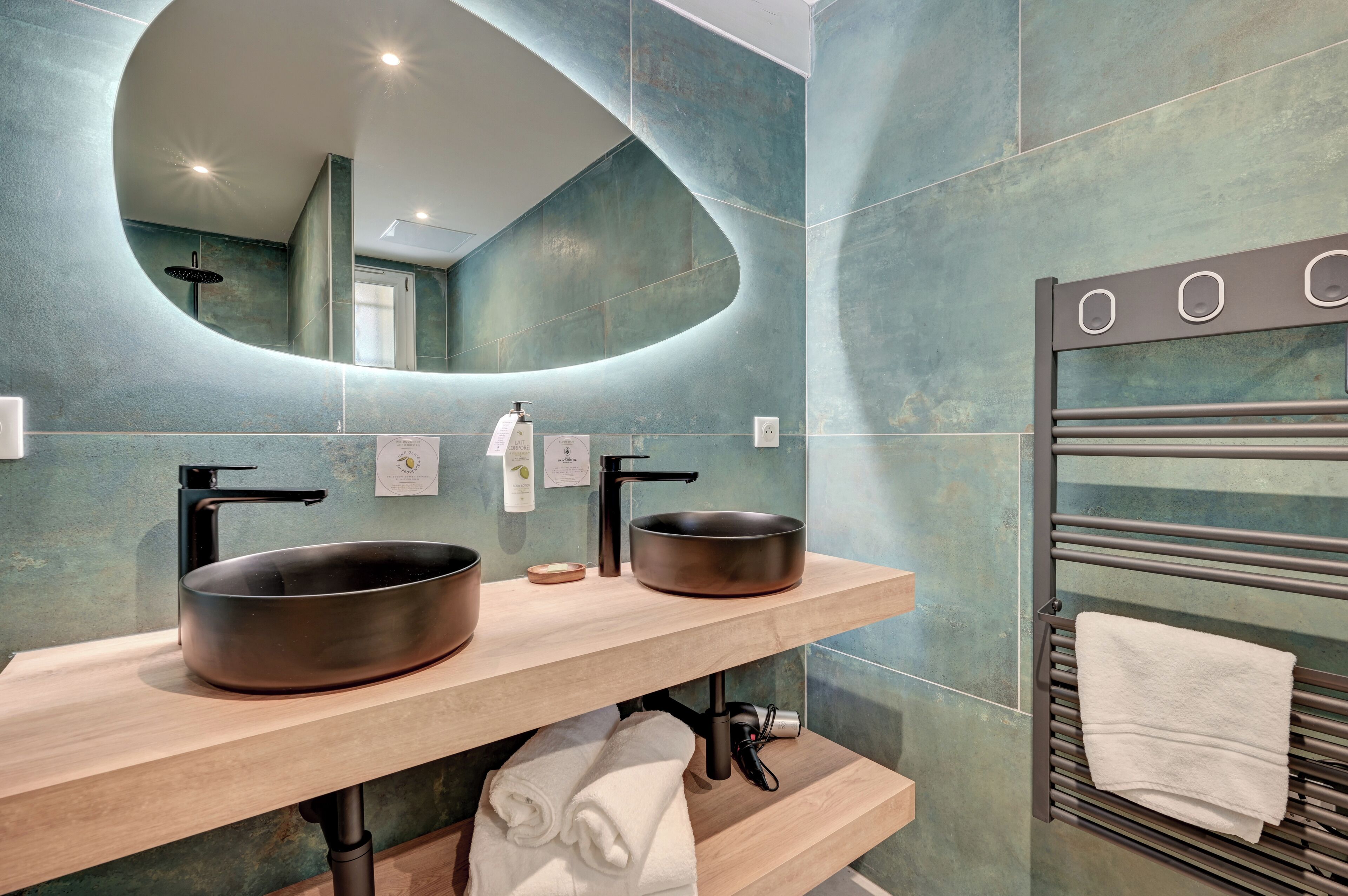 Ein modernes Badezimmer mit zwei Waschbecken, einem großen Spiegel und einem Handtuchhalter.
