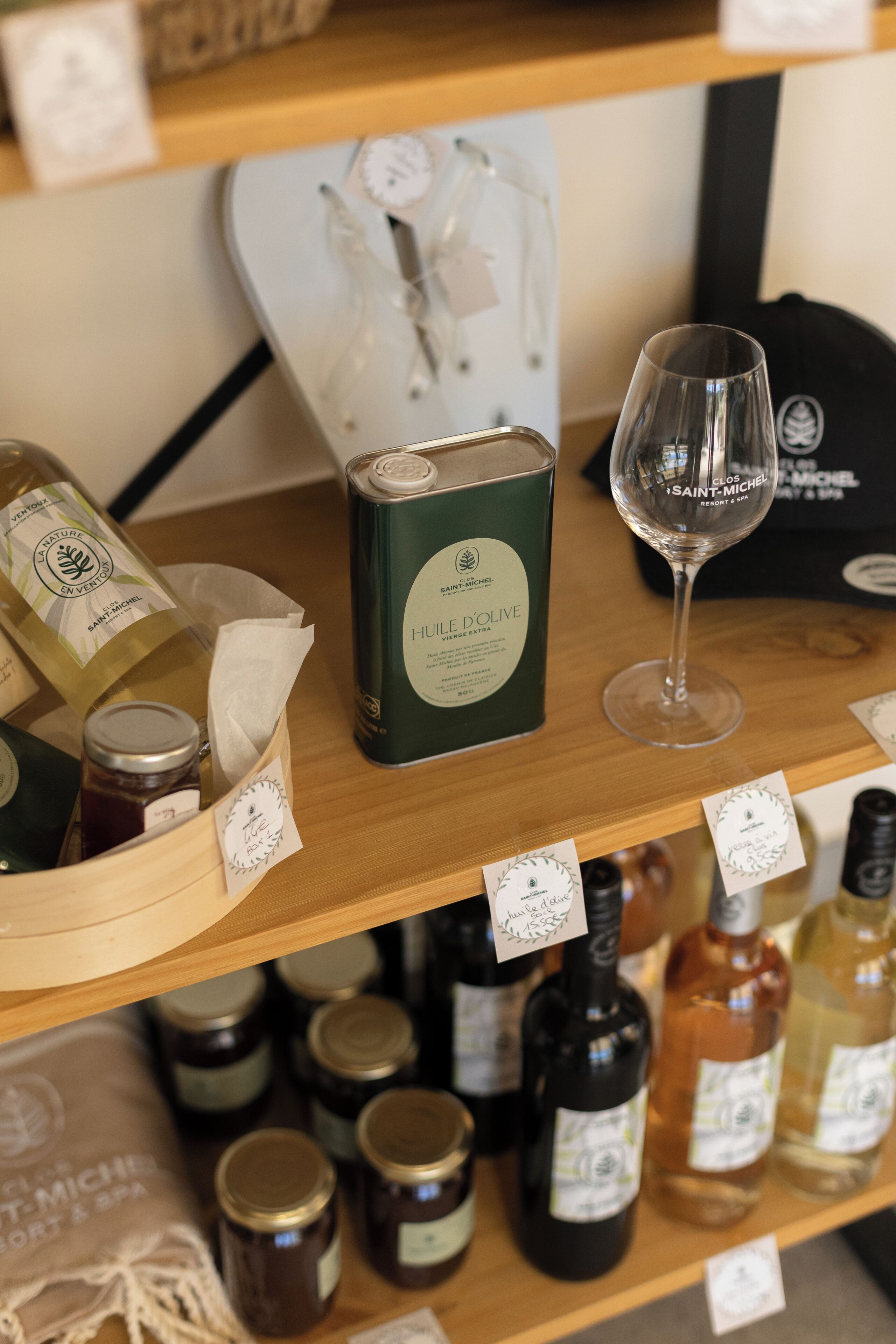 Una estantería de madera con varias botellas y una copa de vino, algunas con etiquetas a la vista.