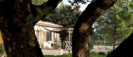 Un edificio rustico con tetto in tegole, circondato da alberi e prato.