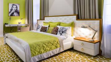 A modern bedroom with a bed, bedside table, lamp, and a desk with a chair.