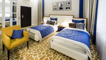 A hotel room with two beds, a yellow armchair, and a patterned carpet.