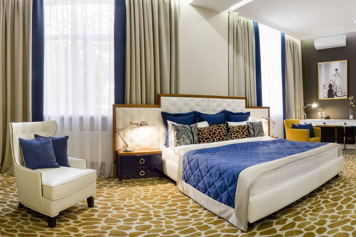 Een hotelkamer met een groot bed, een stoel, een bureau en een kamerbreed tapijt met een patroon.
