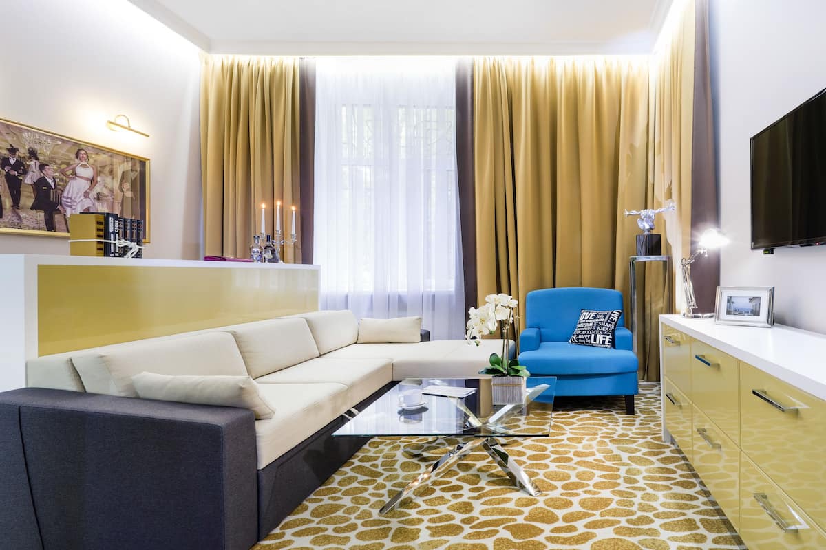 Een moderne woonkamer met een hoekbank, een glazen salontafel, een blauwe fauteuil en een kamerbreed tapijt.