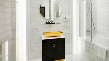 A modern bathroom with a white and black vanity, a round mirror, a yellow sink, and a glass-enclosed shower.