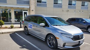 A silver minivan parked in a lot with a sign indicating it is a Holiday Inn Express & Suites.