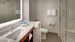 Ein modernes Badezimmer mit einer gläsernen Duschkabine, einem weißen Waschbecken und einer Toilette.