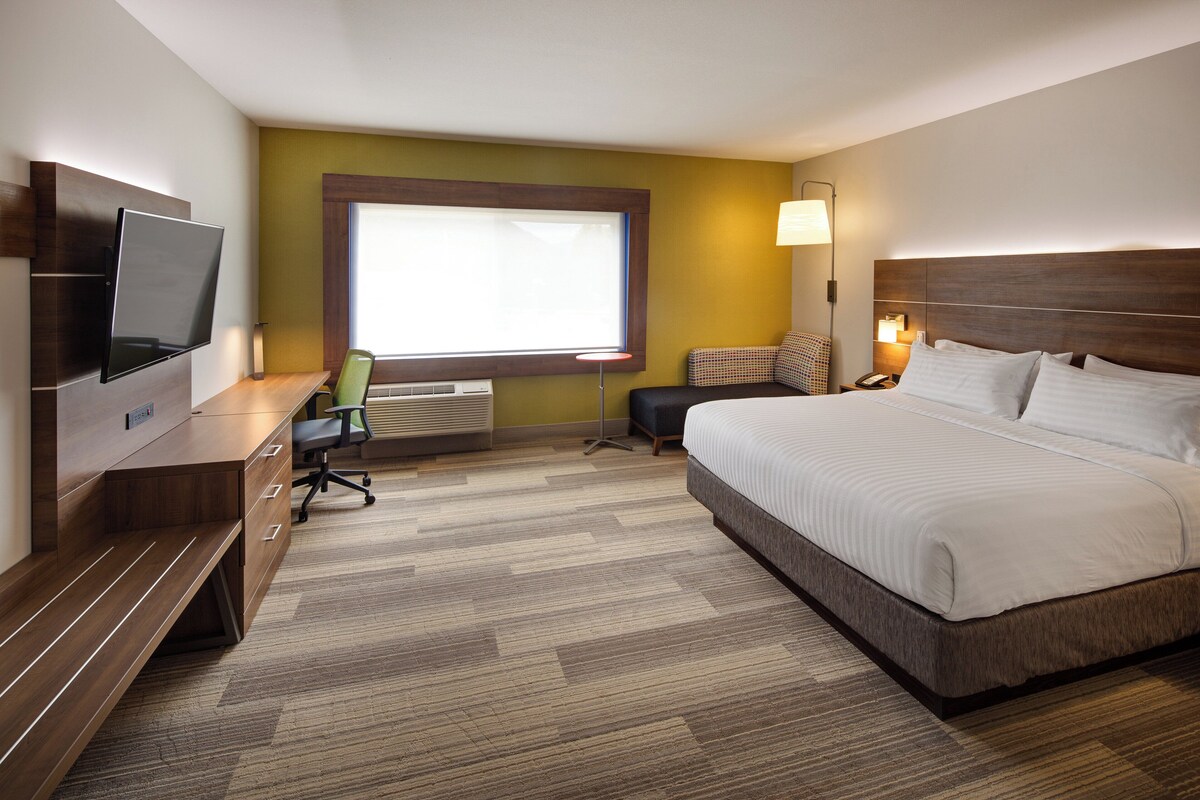 Habitación de hotel con cama, escritorio, silla, televisor y ventana.