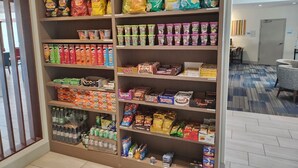 Ein Bereich mit Snacks und Getränken, darunter Produkte wie Lay's Chips, Twix und abgefüllte Getränke.