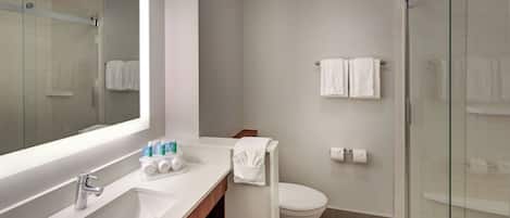 Un baño moderno con lavamanos, espejo, inodoro y cabina de ducha de vidrio.