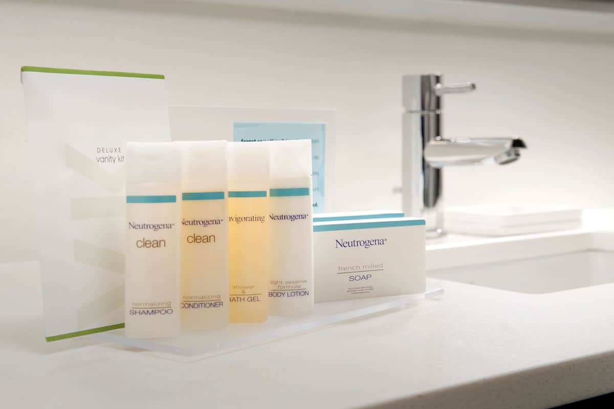 A bathroom with a white sink and three Neutrogena products: shampoo, body lotion, and soap.