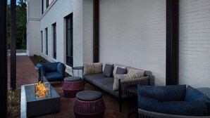 An outdoor patio with a fire feature, seating, and a white brick wall. - Hampton Inn Huntsville/Village of Providence (Huntsville)
