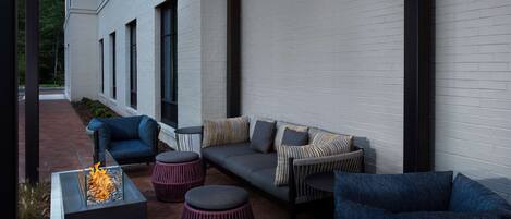 An outdoor patio with a fire feature, seating, and a white brick wall.