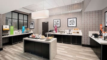 A modern kitchen with a central island, black cabinets, and a patterned wallpaper design.