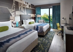 Quarto de hotel com duas camas, uma escrivaninha, uma cadeira e uma janela grande com vista para árvores.
