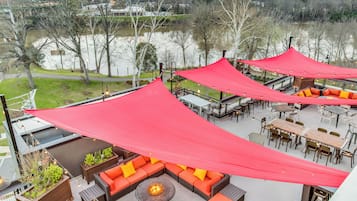 An outdoor seating area with red canopies, a fire pit, and a view of a lake.